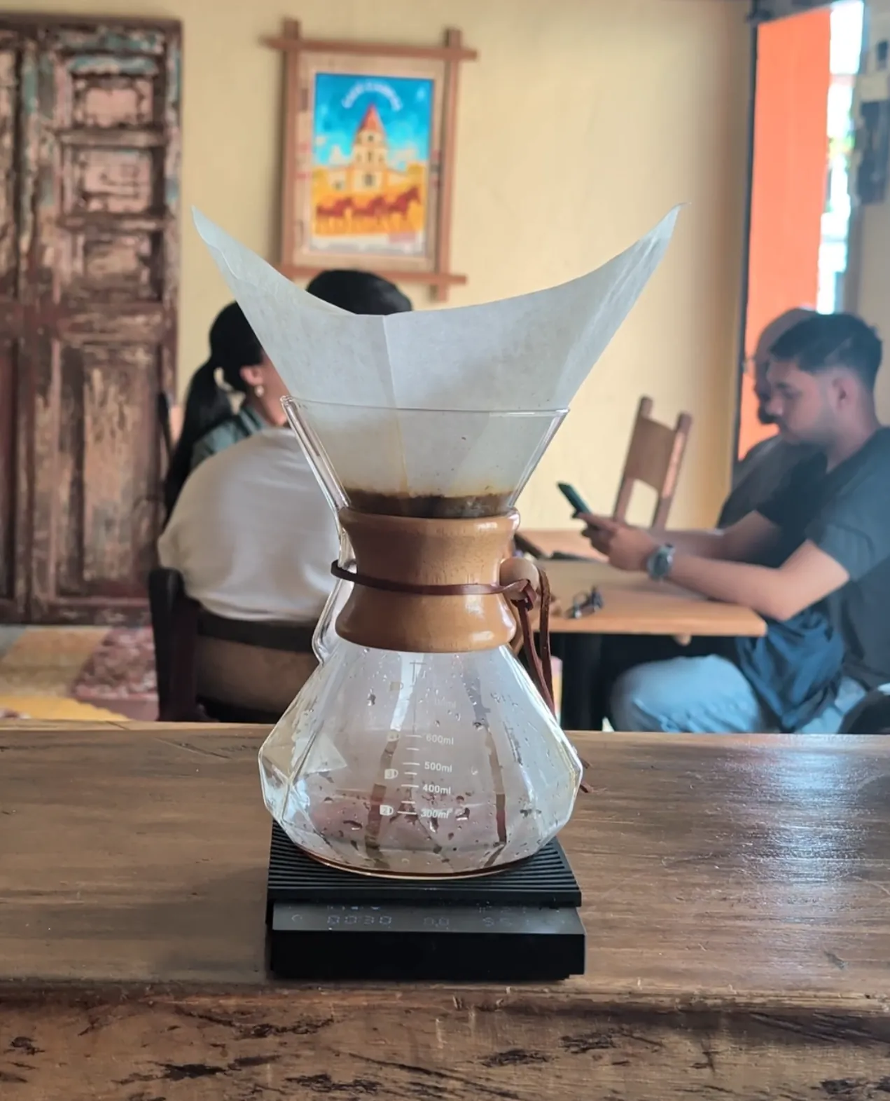 Chemex con filtro y personas al fondo en Café Cabras